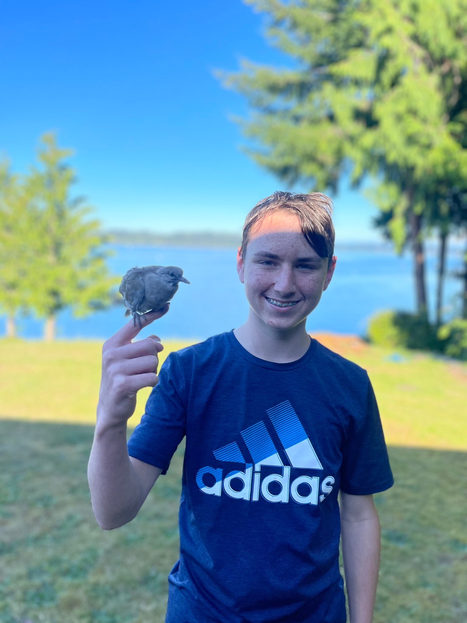 teenager holding his hand up with a bird sitting on it.