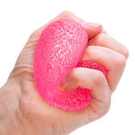 A hand squishes the pink Gumdrop Nee Doh.