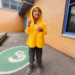 A child smiles while they wear the hood up on the yellow Sensory Friendly Hoodie.