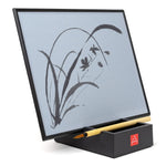 The Original Buddha Board perched on a desk top carrier with the bamboo brush.