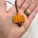 A hand holding the Pumpkin Fidget Necklace.
