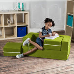 A child sitting on the Lime Jaxx Zipline Modular Kids Loveseat and Ottomans. One of the cushions is on the floor next to the Loveseat and the other cushion is still in the Loveseat and being used as a desk.