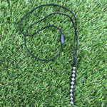 Kaiko Caterpillar Unisex Necklace laying in grass.