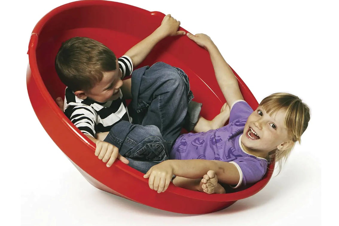 Two children in a red Gong Giant spinning top with a white background