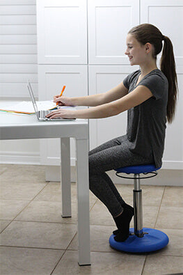 Teen sitting on a wobble stool at a desk working