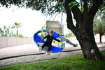 A child with light skin tone and short blonde hair swings back with their legs out in front of them on the Slackers 50" Adventure Sky Swing.