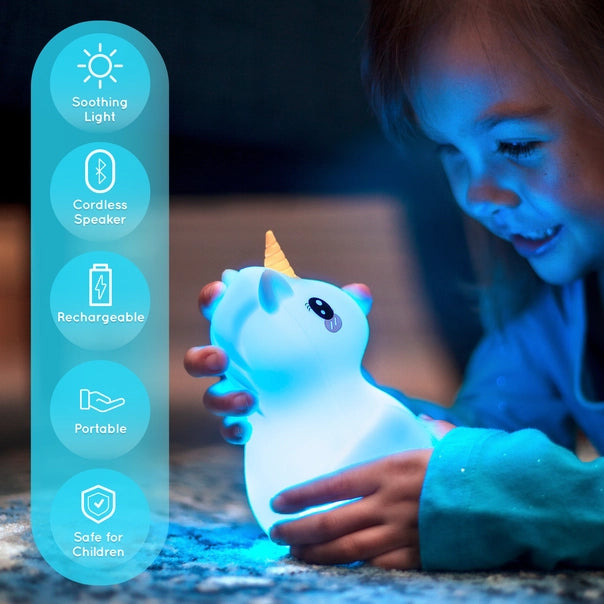 A child holds onto a luminous Unicorn LumiPets Bluetooth Speaker Night Light.