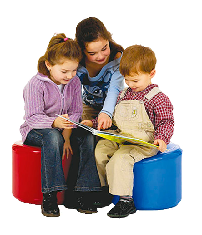 Two children sit on both the red and blue Dynair Balance Seat with an open book while a third peers over their shoulder.