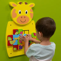 A child with light skin tone and short brown hair moves the tiles on the Giraffe Mosaic Fruits Wall Toy.
