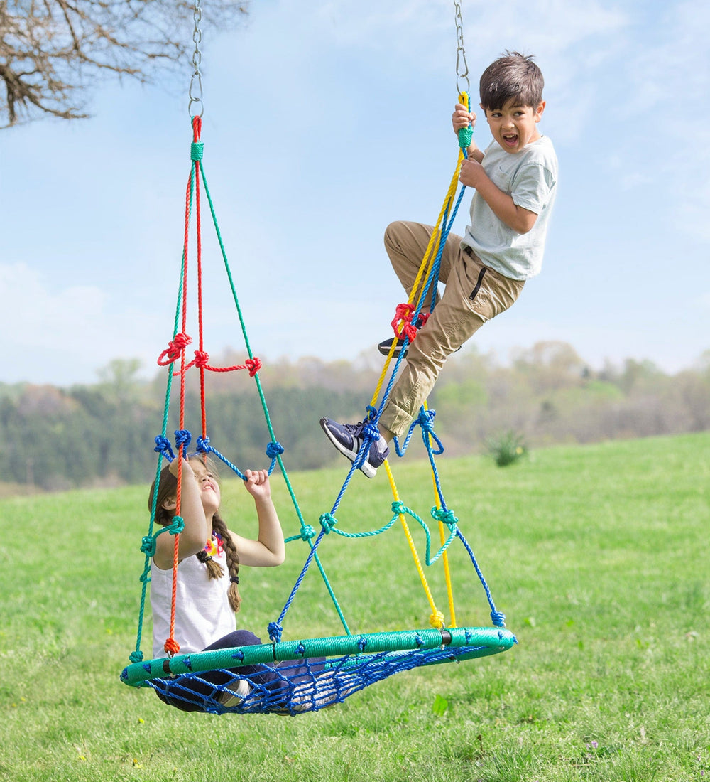 One child sits on the swing and leans back on the climbing nets. Another child climbs the net and reaches the top.
