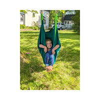 A child with light skin tone and short blonde hair is sitting in the Slackers Swing Hammock.