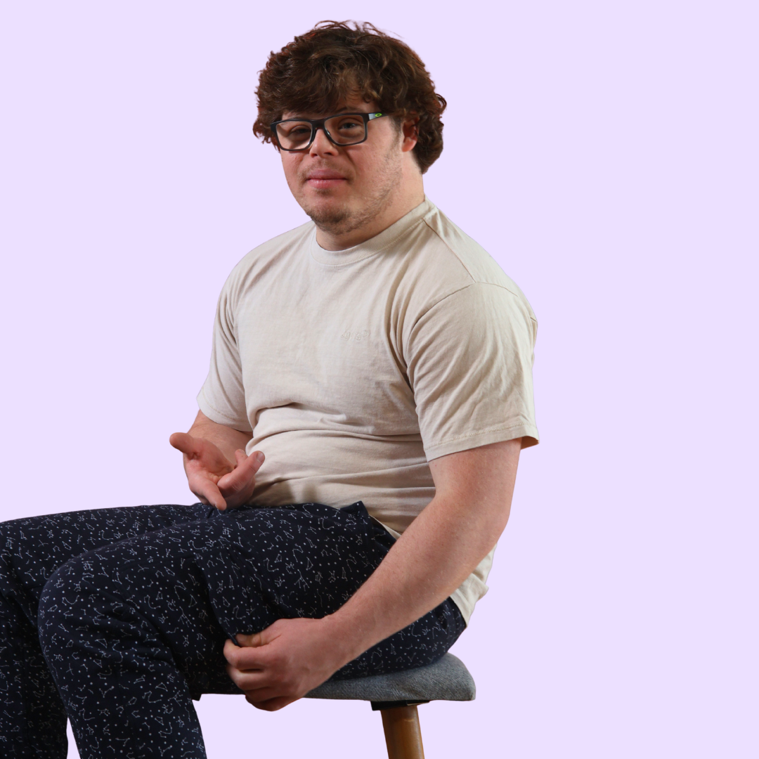 An adult sits down to model the Constellation Adult Sensory Friendly Fidget Joggers.