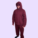 An adult wears the Maroon Sensory Hoodie for Adults with the eye mask pulled down.