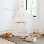 The terrazzo beige Play Tent Castle is sitting on a brown rug next to several containers full of toys and a xylophone.