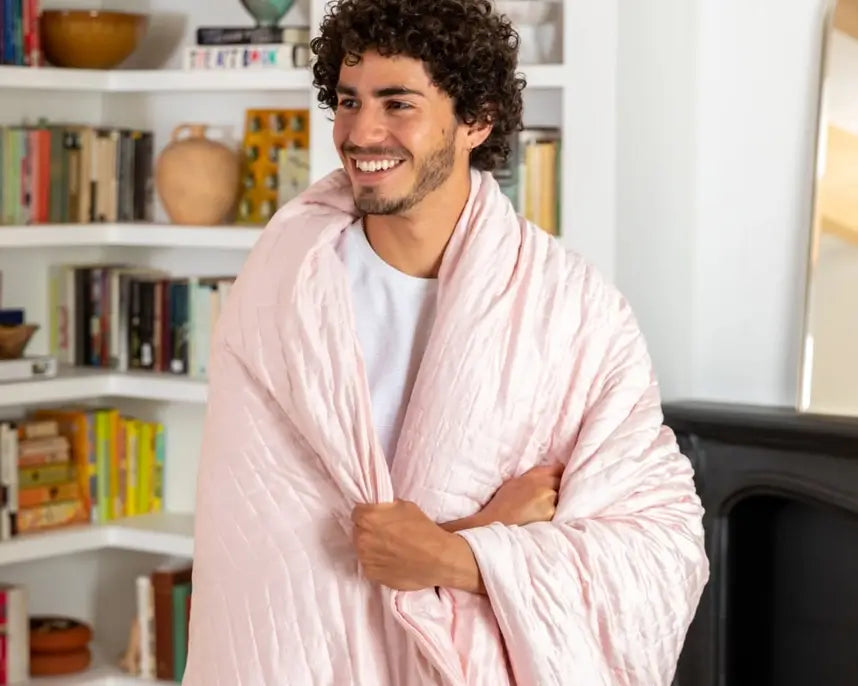 A person wearing the pink Gravity Cooling Weighted Blanket (20 lbs).