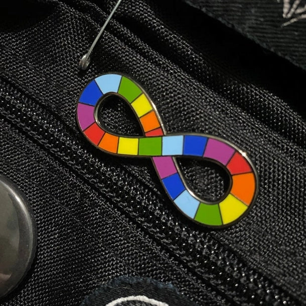 The Neurodiversity Pride Enamel Pin on a black item.