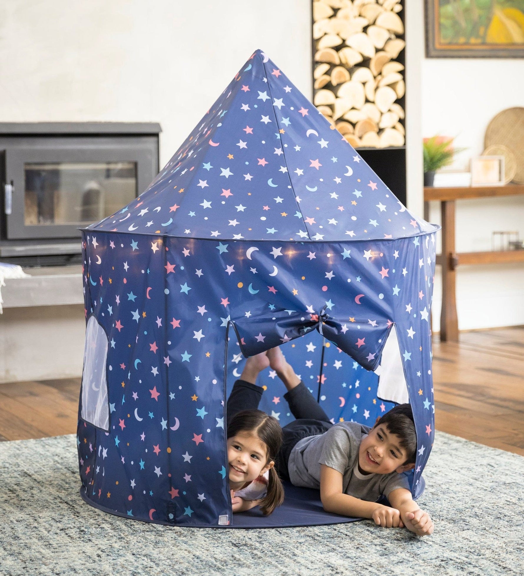 Two children peep their heads out of the Light-Up Celestial Play Tent.