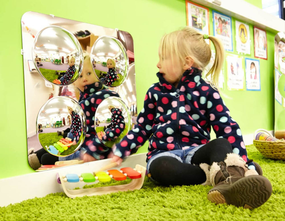 A child sits in front of the Large 4 Bubble Dome Sensory Mirror.