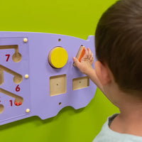 A close up look at a child with light skin tone and short brown hair playing with the shapes on the Hippo Activity Wall Panel.