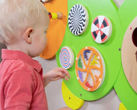 A child plays with the wheels on the Caterpillar Activity Wall Panel.