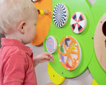 A child plays with the wheels on the Caterpillar Activity Wall Panel.