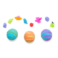 A stylized photo of the three colors of Tie Dye Dinosaur Mystery Bath Bomb with the assorted types of squishy dinosaurs floating above them.