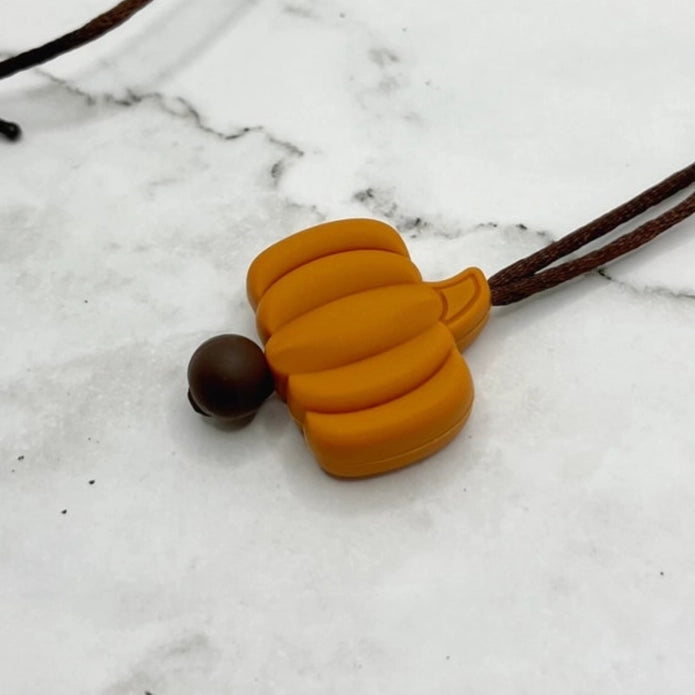 The Pumpkin Fidget necklace on a marble table.