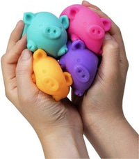 A hand with light skin tone holds up all four colors of the Dig It Pig.