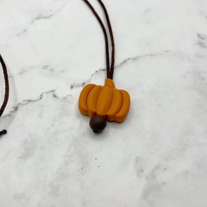 The Pumpkin Fidget Necklace on a marble table.