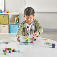 A child with medium skin tone and short brown hair plays at a table with the Mathlink Cubes, Numberblocks 1-10.