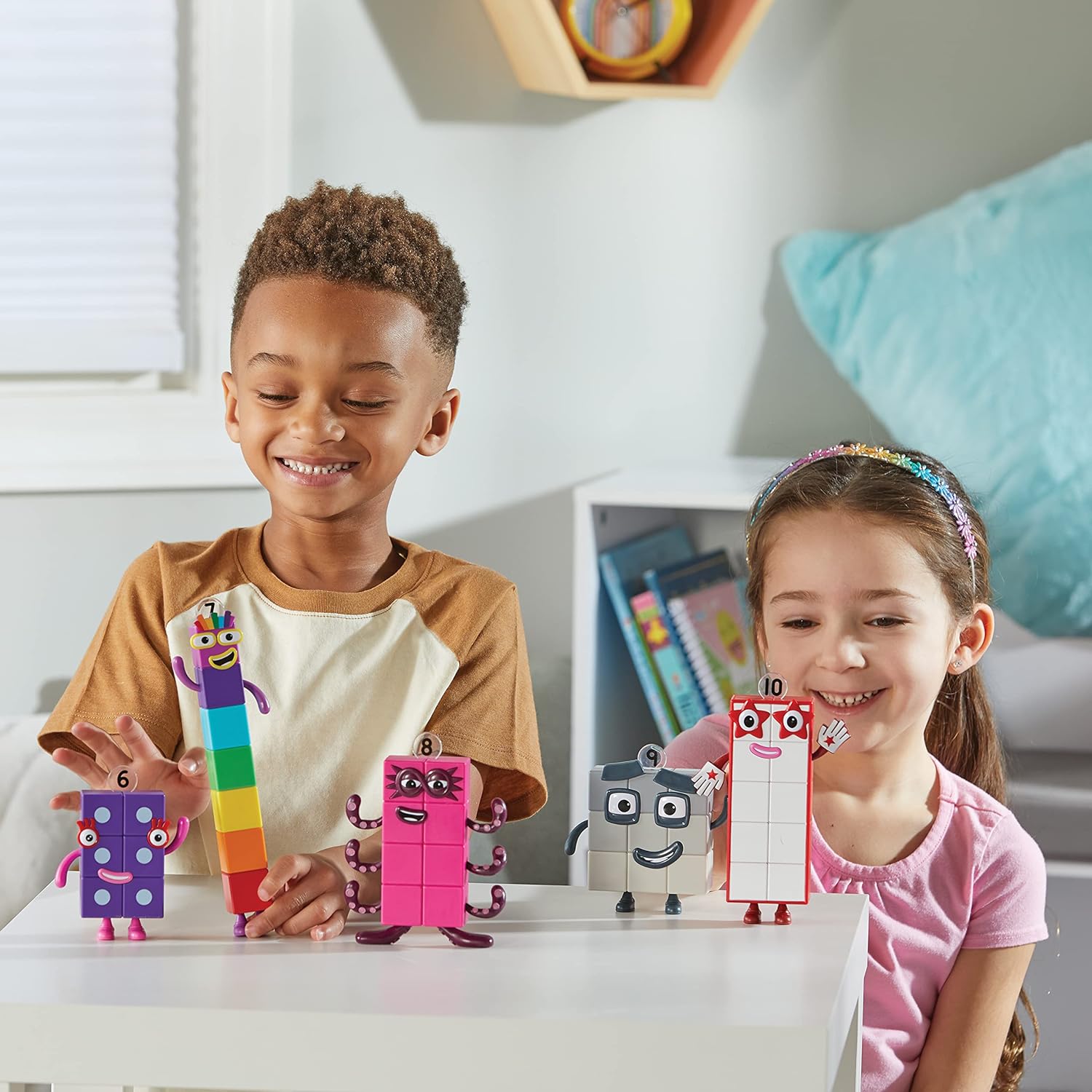 Two children smile while standing behind the Numberblocks Figures 6-10.