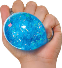 A hand with light skin tone squeezes the blue Crystal Nee Doh.