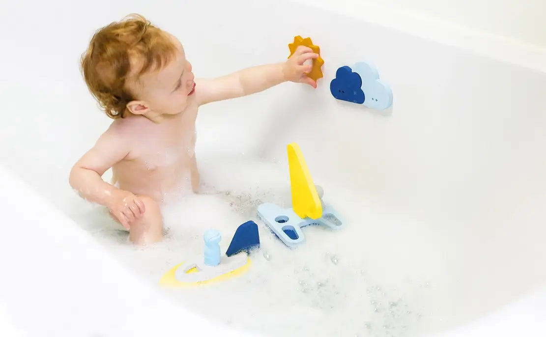 A child in the tub reaches for a piece of Sail Away Bath Puzzle Toys.