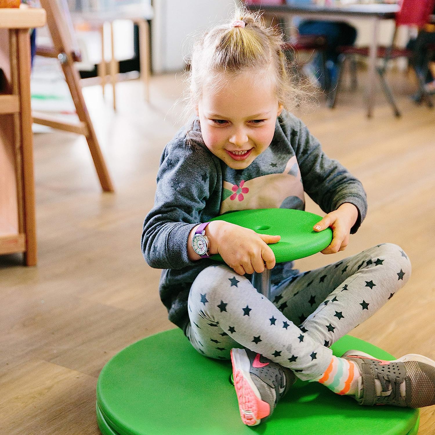 A child sits on the Whizzy Dizzy with their legs crossed.