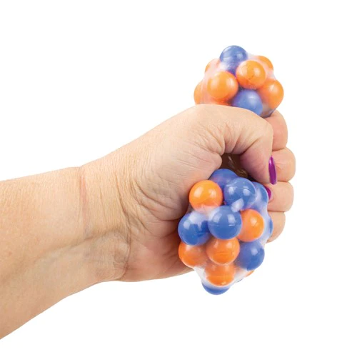 A hand with light skin tone and purple nail polish squeezes Click Clack Molecule Ball.