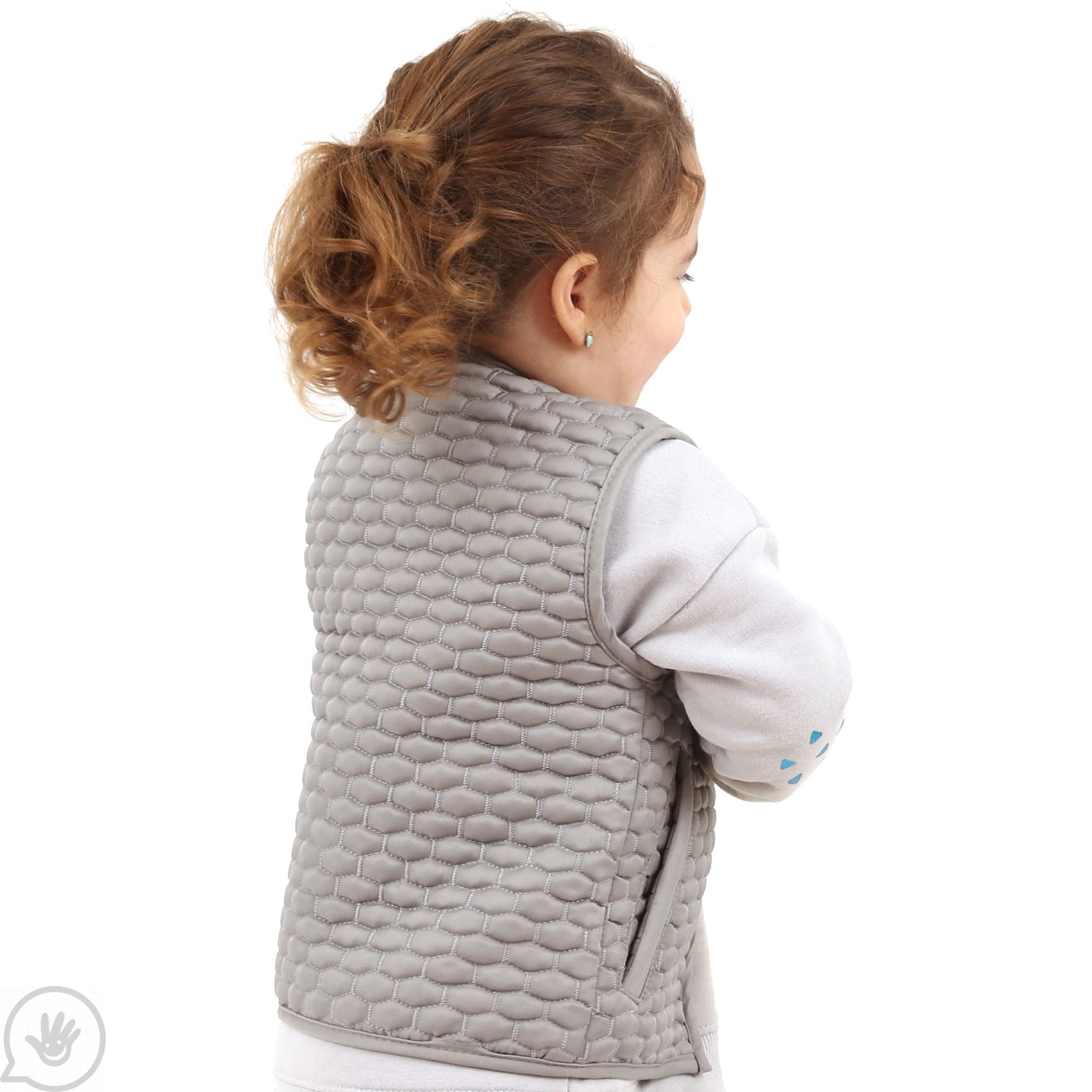 A child with light skin tone and a curly brown pony tail stands with their back to the camera to show the backside of the Kids Honeycomb Weighted Vest.