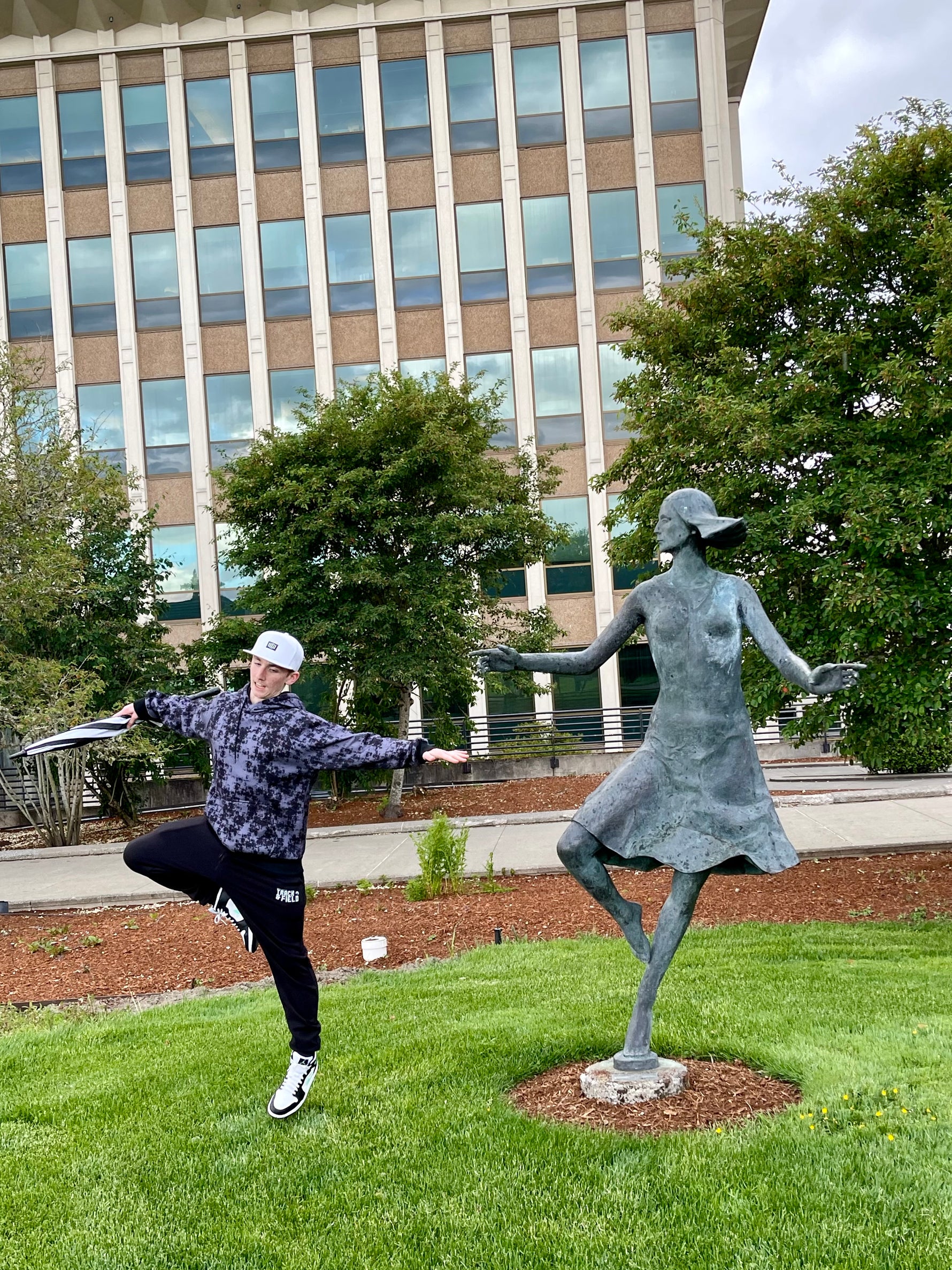 Teen boy standing like a statue in a park