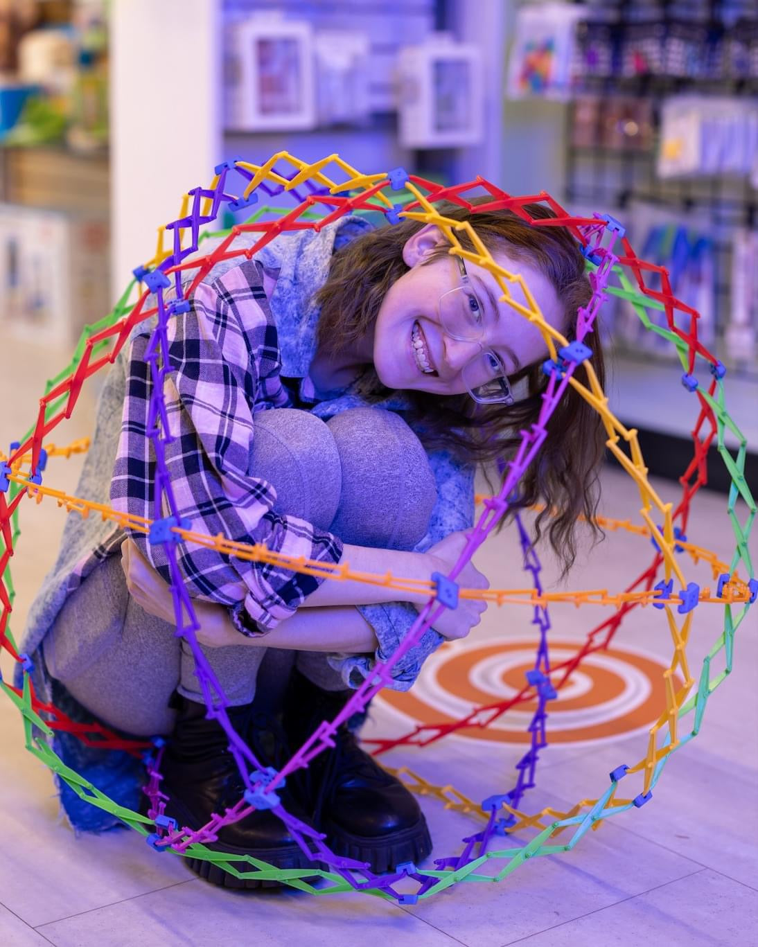 woman in a crouched ball position inside a hoberman sphere