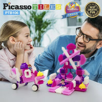 An adult with light skin tone and short brown hair with a greying beard and glasses smiles at a young child with light skin tone and blonde hair that is pulled back. They are at a table that is displaying two different designs built with the Pink Castle Themed BristleLock Building Block Set.