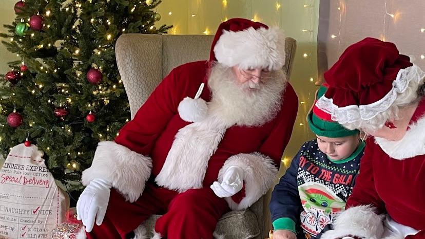 Boy sits with Santa and Mrs. Claus