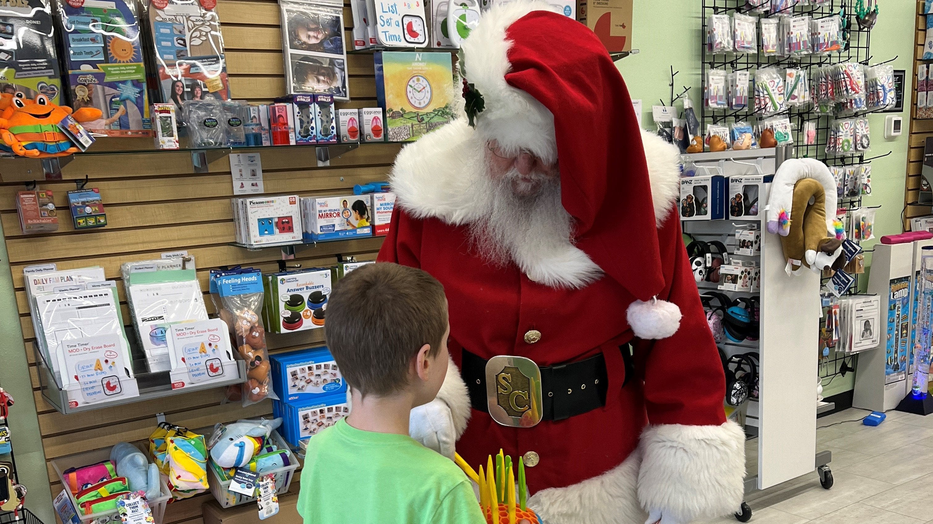 Santa plays with a toy in a store with a young boy