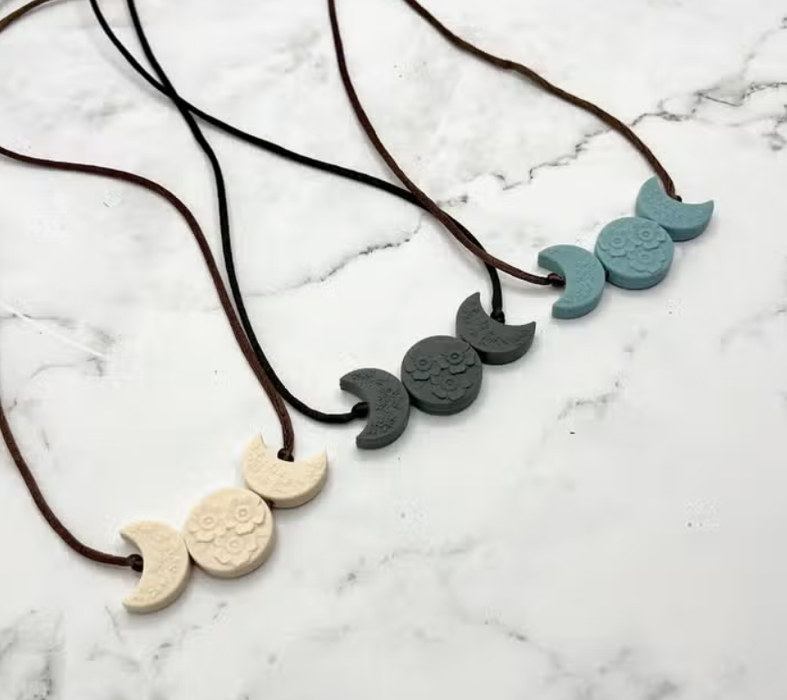 Several colors of the Crescent Moon Phases Fidget Necklace.