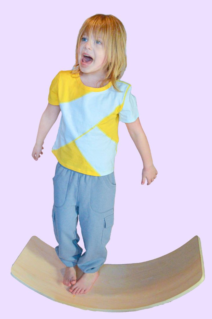 A child stands on a balance board in the Yellow and Mint Easy to See Sensory Friendly T-Shirt.