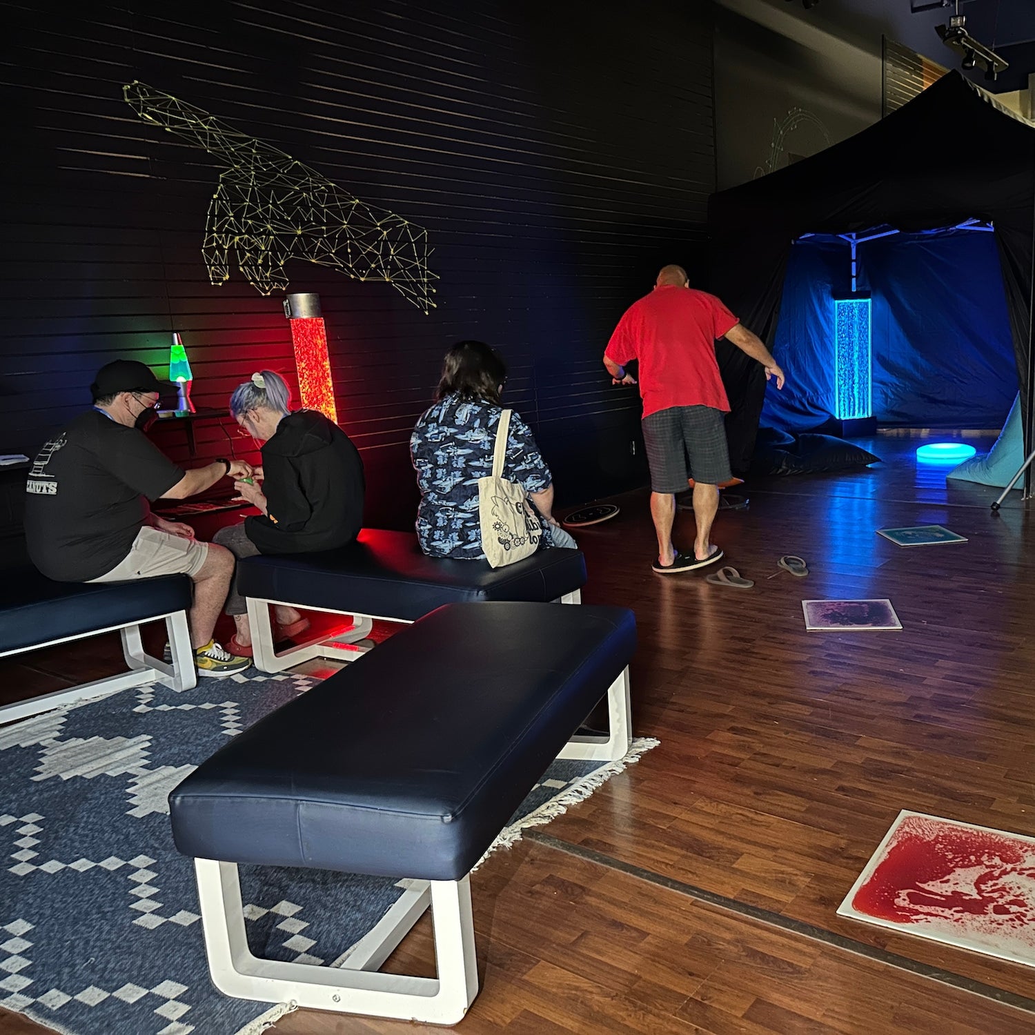 adults using a sensory room with bubble tubes and balance boards