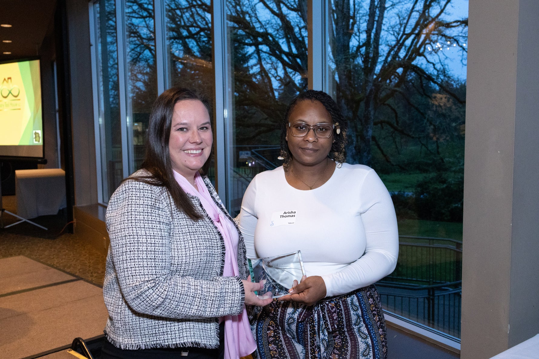 Two women smiling at the camera holding an award