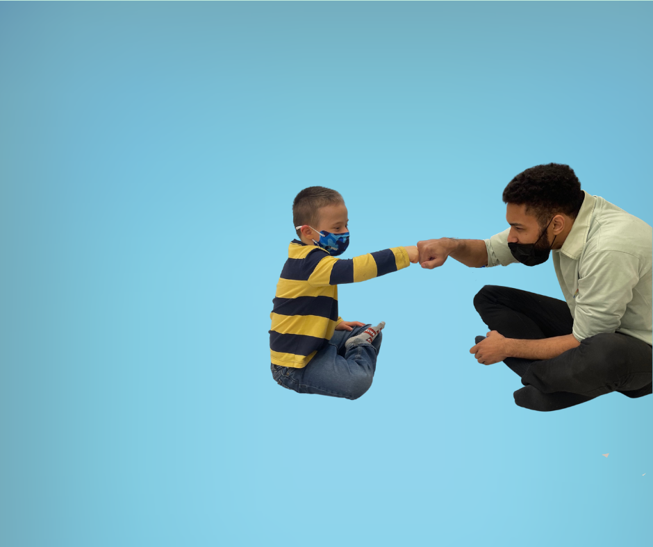 Man and young boy sitting on the floor giving a fist bump