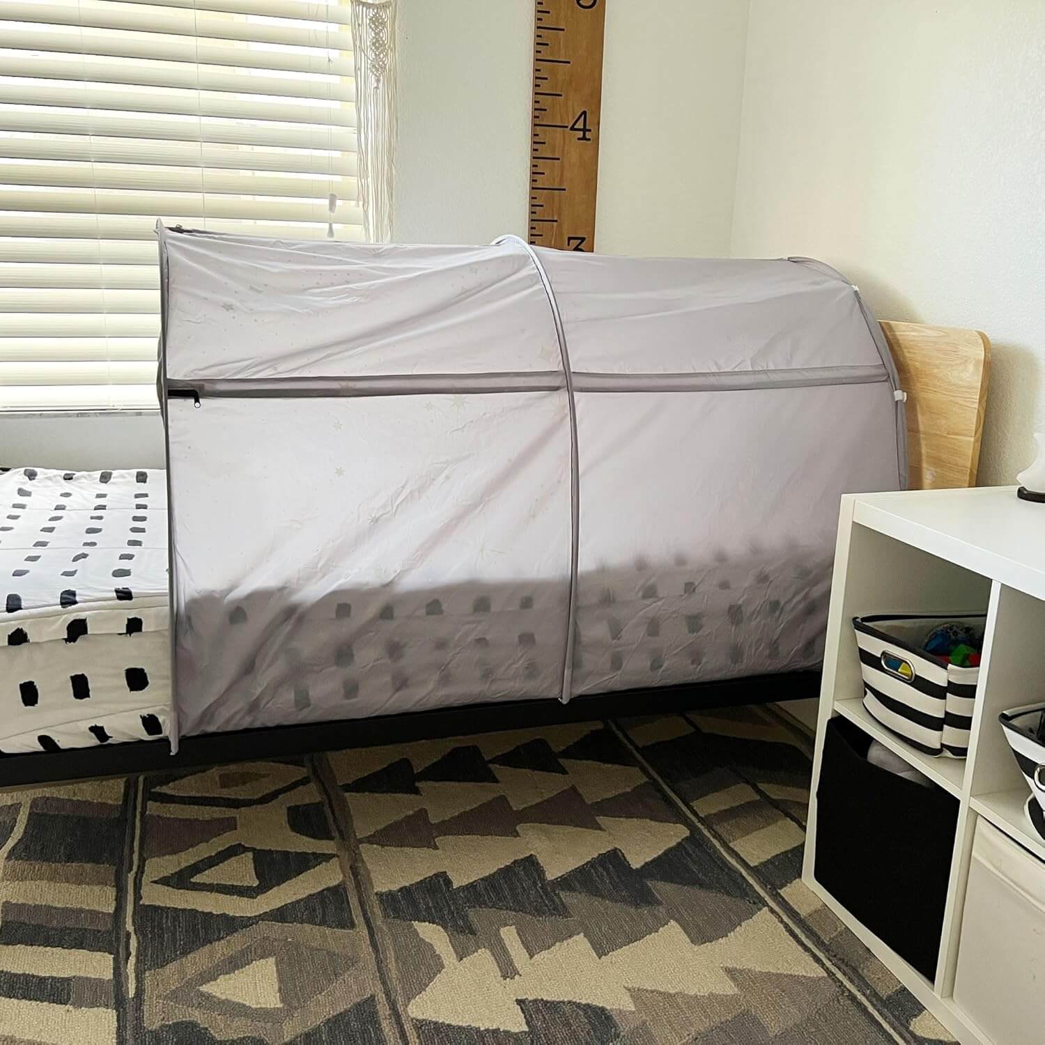 The Mod About Gray DreamFort set up on a twin bed, situated between a window and a shelf.