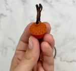 A hand showing the design on the top of the Acorn Fidget Chewable Jewelry Necklace.