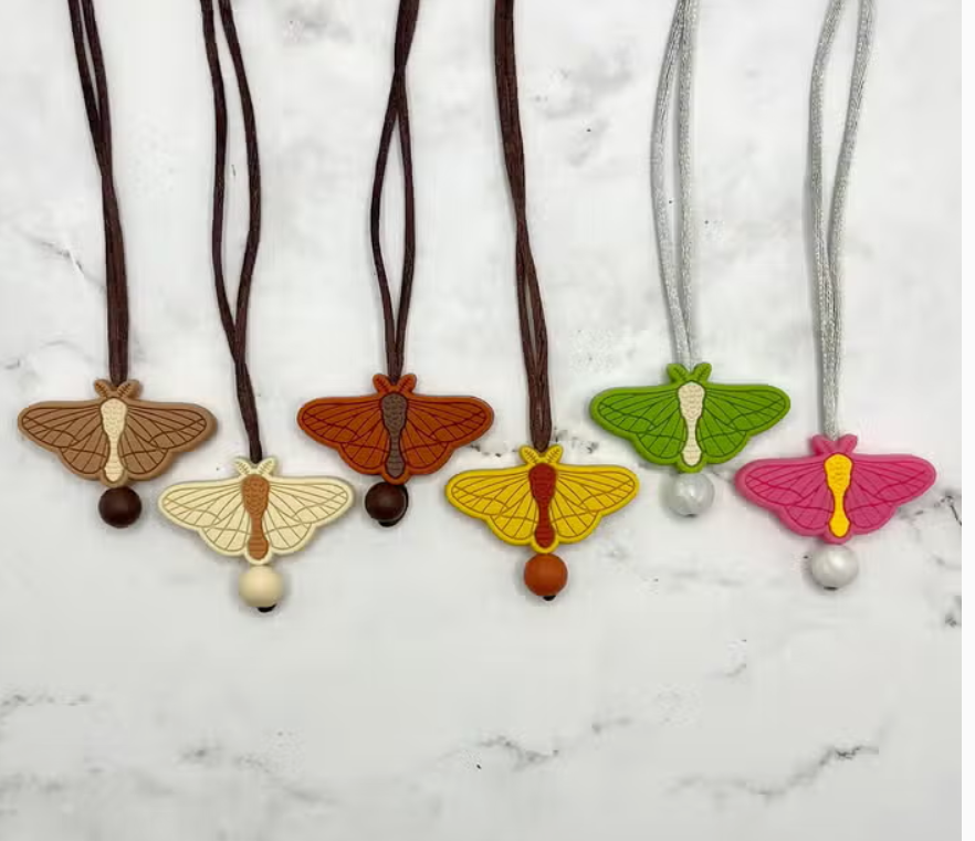 A colorful array of the Moth Fidget Chewable Jewelery Necklace.