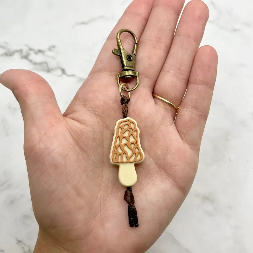 A hand holds the Morel Chewy Fidget Zipper Pull/Keychain.